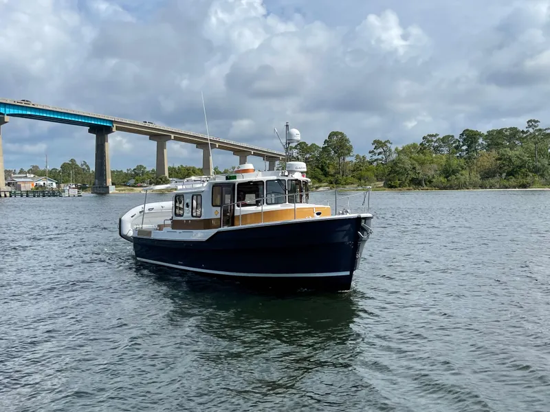 Slide: The Image of 2025 Ranger Tugs R-31S cruising on a river near a bridge. - 3
