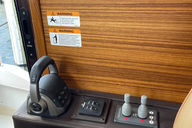 Slide: The Image of Control panel of 2025 Ranger Tugs R-31S with warning labels and joystick controls. - 32