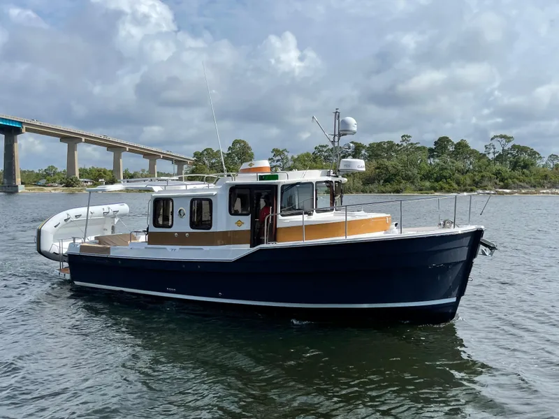Slide: The Image of 2025 Ranger Tugs R-31S boat cruising on a river near a bridge. - 4