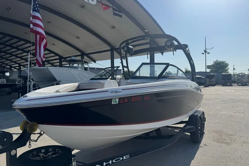 Slide: The Image of 2018 Tahoe 700 TF boat on trailer, parked under a canopy with American flag. - 3