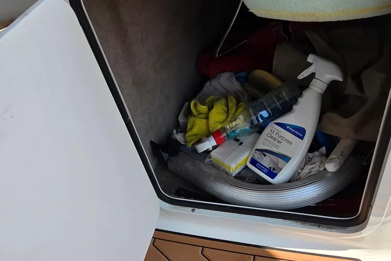Slide: The Image of Storage compartment on a 2003 Sea Ray 280 Sundancer with cleaning supplies and tools. - 15