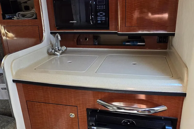 Slide: The Image of 2003 Sea Ray 280 Sundancer galley with sink, microwave, and storage cabinets. - 20