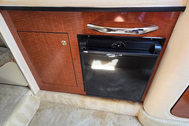 Slide: The Image of 2003 Sea Ray 280 Sundancer interior with wood cabinetry and compact refrigerator. - 21