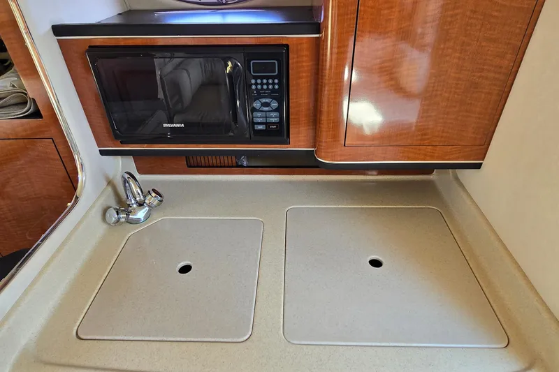 Slide: The Image of 2003 Sea Ray 280 Sundancer kitchen with microwave, sink, and wooden cabinetry. - 22