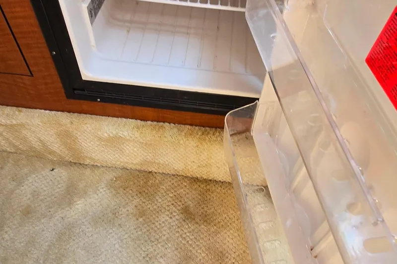 Slide: The Image of Open fridge inside 2003 Sea Ray 280 Sundancer boat, showing interior and carpeted floor. - 24