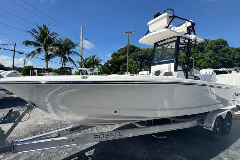 Slide: The Image of 2025 Robalo 246 Cayman SD boat on trailer, palm trees in background. - 1