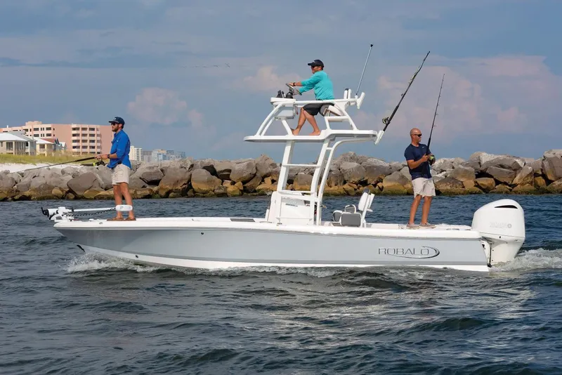 Slide: The Image of Manufacturer Provided Image: 2025 Robalo 246 Cayman SD boat with three people fishing near rocky shoreline. - 27