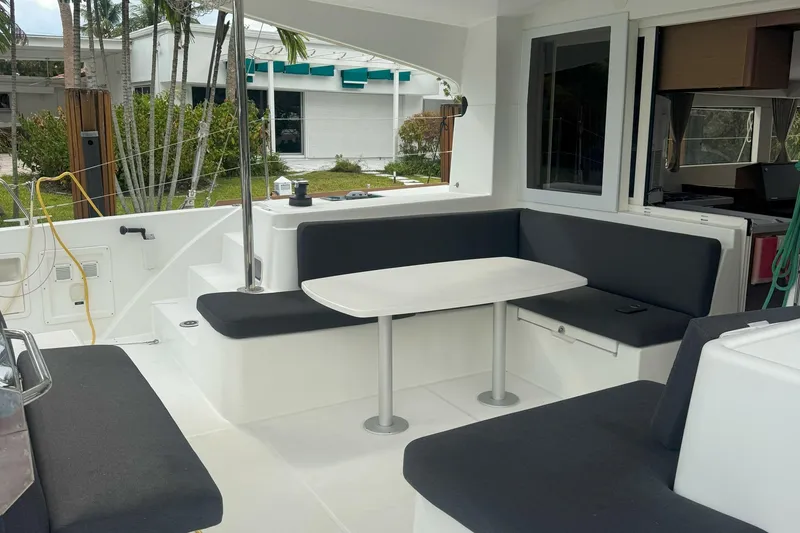 Slide: The Image of Outdoor seating area on a 2022 Lagoon 40 catamaran, featuring a table and cushioned benches. - 17