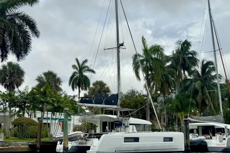 Slide: The Image of 2022 Lagoon 40 catamaran docked near palm trees under cloudy skies. - 2
