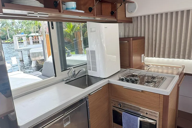 Slide: The Image of Modern kitchen interior on a 2022 Lagoon 40 catamaran, featuring stove, sink, and scenic window view. - 35