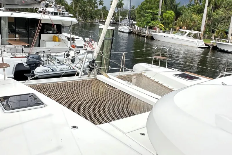 Slide: The Image of 2022 Lagoon 40 catamaran docked with dinghy, surrounded by lush greenery and other boats. - 4