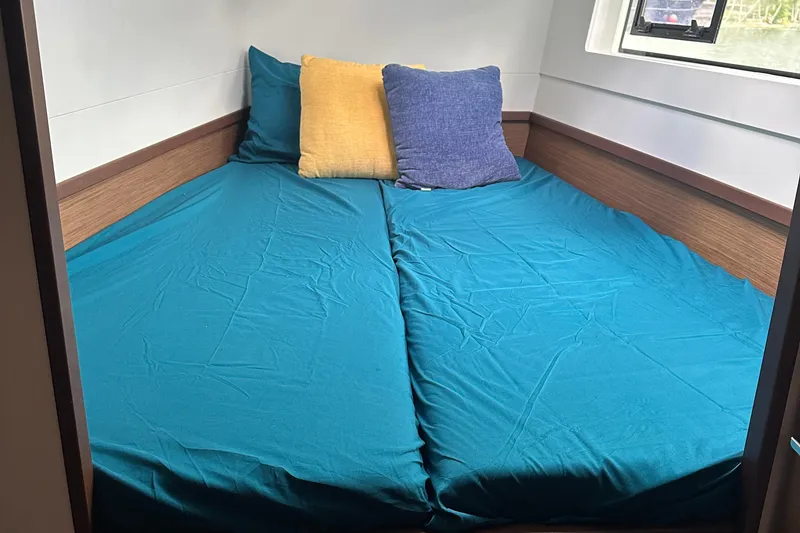 Slide: The Image of Interior cabin of 2022 Lagoon 40 catamaran with teal bedding and colorful pillows. - 45