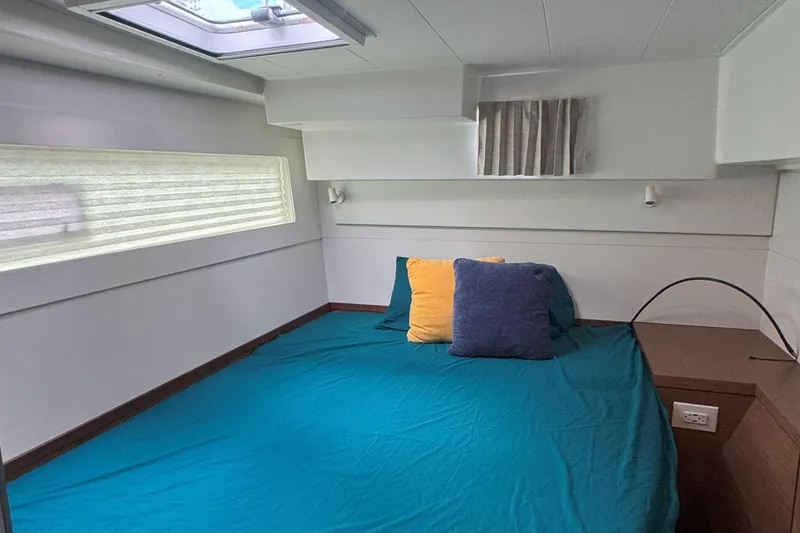 Slide: The Image of Interior cabin of 2022 Lagoon 40 catamaran with bed, pillows, and window. - 50