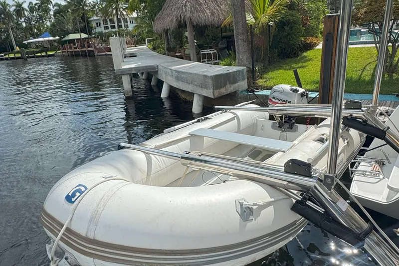Slide: The Image of Inflatable boat docked by a wooden pier, featuring a Mariner outboard motor. - 57