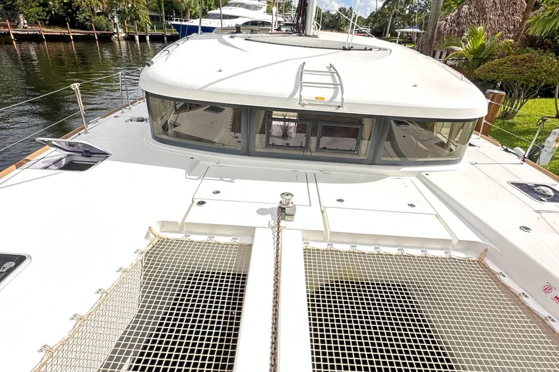 Slide: The Image of 2022 Lagoon 40 catamaran deck with netting, docked by lush greenery. - 6