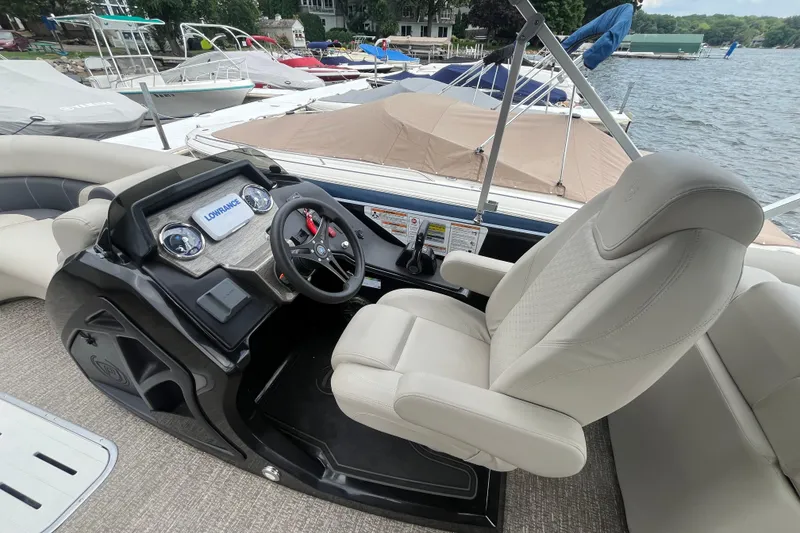 Slide: The Image of Captain's seat and helm of 2020 Premier 230 SunSation RF pontoon boat at a lakeside dock. - 40