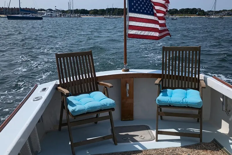 Slide: The Image of Two chairs with blue cushions on a 1981 Dyer 29 boat, American flag waving. - 13