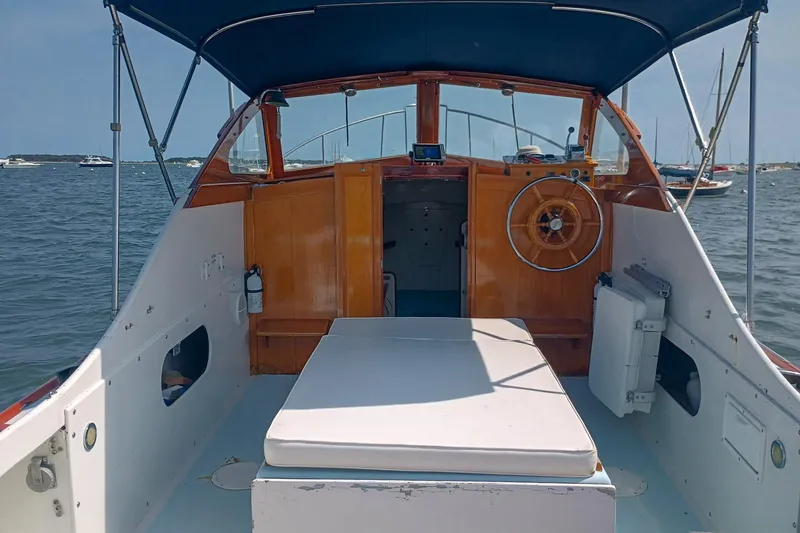 Slide: The Image of 1981 Dyer 29 boat interior with wooden helm, white seating, and blue canopy on the water. - 2