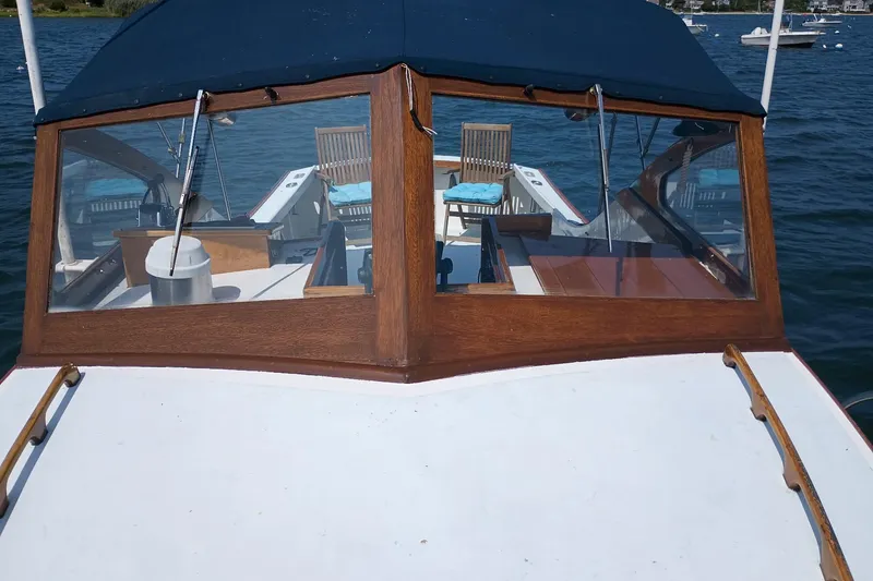 Slide: The Image of 1981 Dyer 29 boat with wooden cabin and blue canopy on the water. - 3