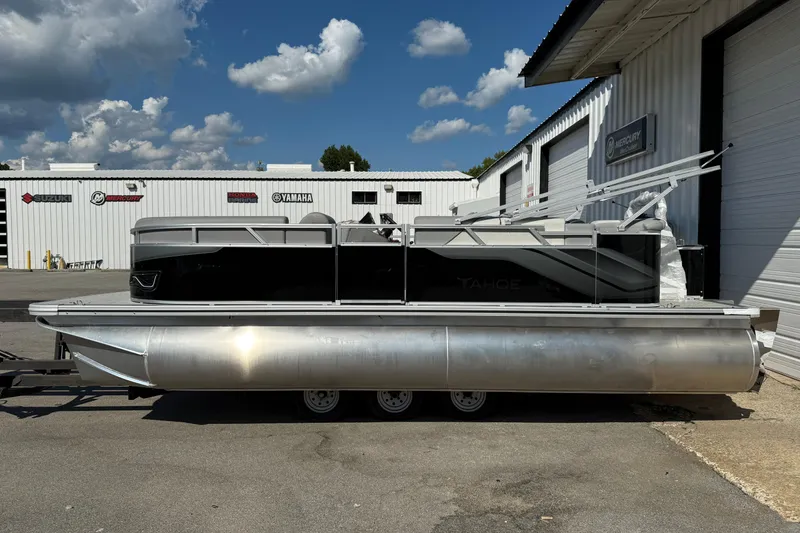 The Image of 2026 Tahoe Pontoon Sport 85 Cruise on trailer, American flag, parked outdoors. - 0