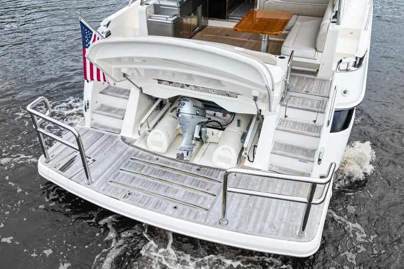 Slide: The Image of 2021 Riviera 5400 Sport Yacht Platinum Edition with open tender garage on water. - 12