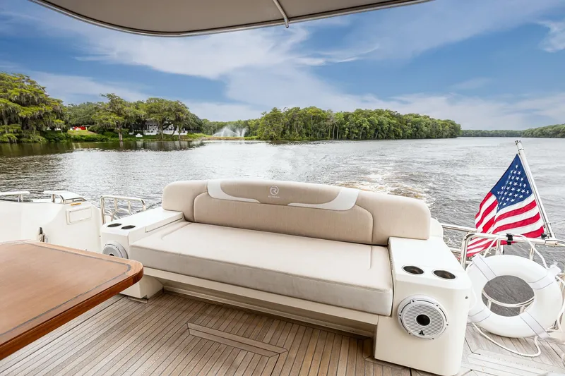 Slide: The Image of 2021 Riviera 5400 Sport Yacht Platinum Edition on serene lake with American flag. - 15