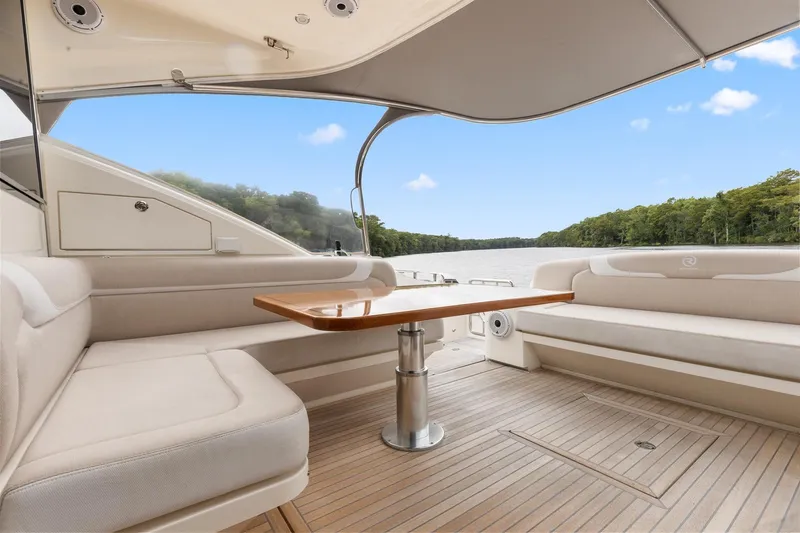 Slide: The Image of 2021 Riviera 5400 Sport Yacht Platinum Edition interior with elegant seating and wooden table. - 17