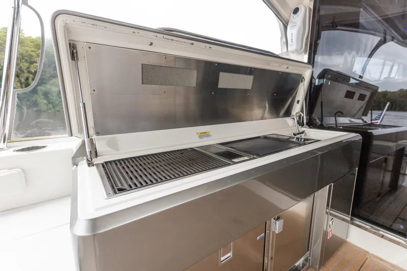 Slide: The Image of Outdoor kitchen on 2021 Riviera 5400 Sport Yacht Platinum Edition, featuring grill and sink. - 22