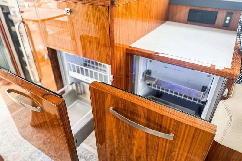 Slide: The Image of Luxurious wooden cabinetry and open fridge in 2021 Riviera 5400 Sport Yacht Platinum Edition. - 35