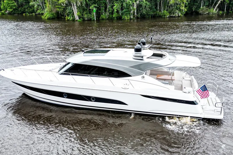 Slide: The Image of 2021 Riviera 5400 Sport Yacht Platinum Edition cruising on a serene river. - 4