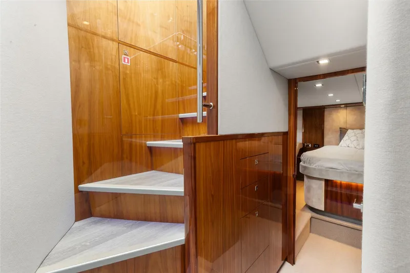 Slide: The Image of Interior of 2021 Riviera 5400 Sport Yacht Platinum Edition, featuring wooden stairs and a cozy bedroom. - 48