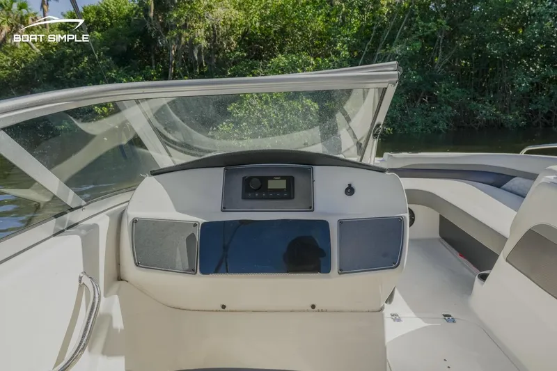 Slide: The Image of 2022 Hurricane SunDeck 217 OB boat dashboard with windshield, surrounded by lush greenery. - 9