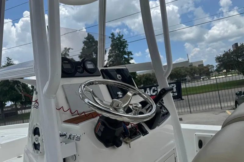 Slide: The Image of 2022 NauticStar 215 XTS boat console with steering wheel and gauges under a cloudy sky. - 10