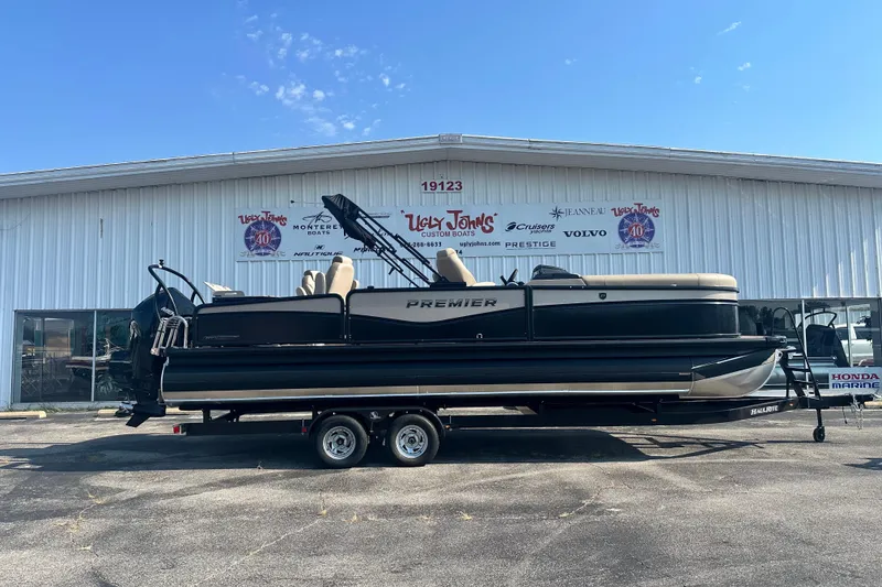 The Image of 2026 Premier 250 Angler pontoon boat on trailer outside dealership. - 1