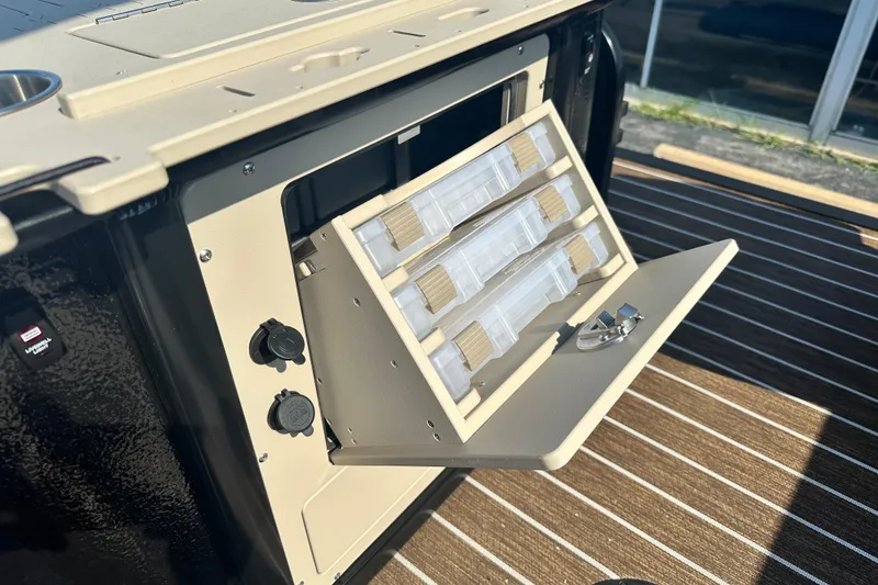 Slide: The Image of 2026 Premier 250 Angler boat storage compartment with tackle boxes and utility outlets. - 15