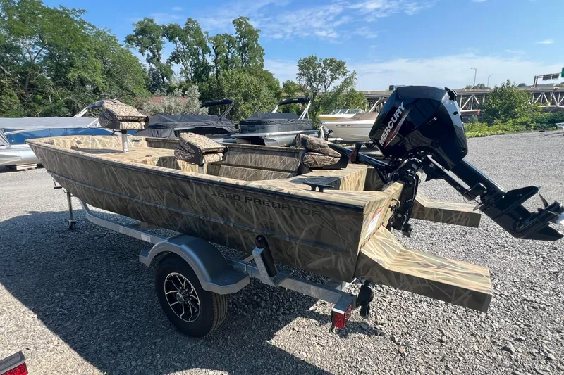 Slide: The Image of 2026 Lund 1660 Predator boat with camo design and Mercury outboard motor on a trailer. - 2