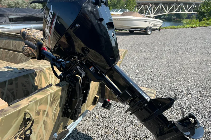 Slide: The Image of 2026 Lund 1660 Predator boat with Mercury outboard motor, parked on gravel near water. - 6