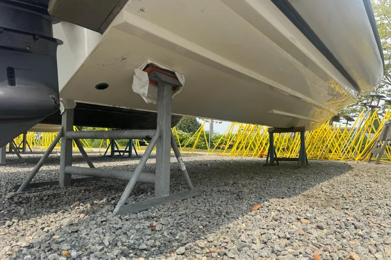 Slide: The Image of 2016 Protector 30 Center Console boat on stands, gravel ground, yellow barriers in background. - 12