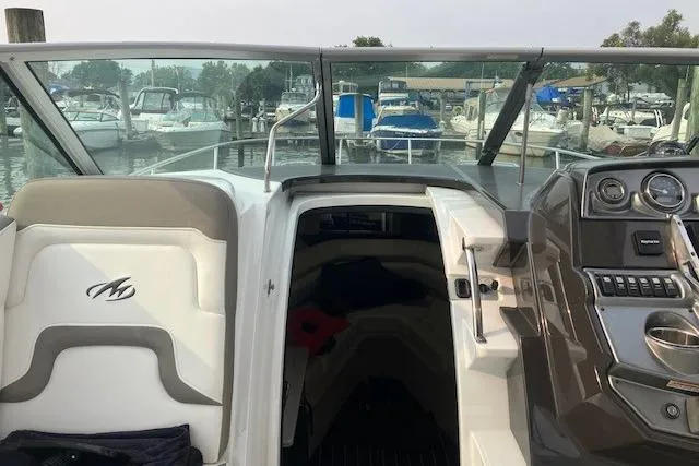 Slide: The Image of 2016 Monterey 275 Sport Yacht interior with dashboard and seating at a marina. - 12