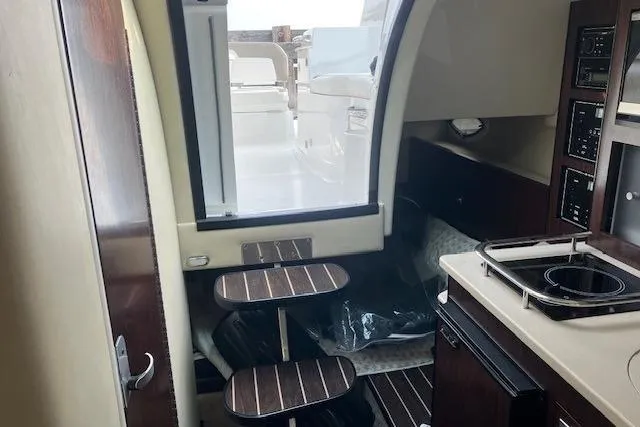 Slide: The Image of Interior of a 2016 Monterey 275 Sport Yacht, featuring a compact kitchen and seating area. - 6