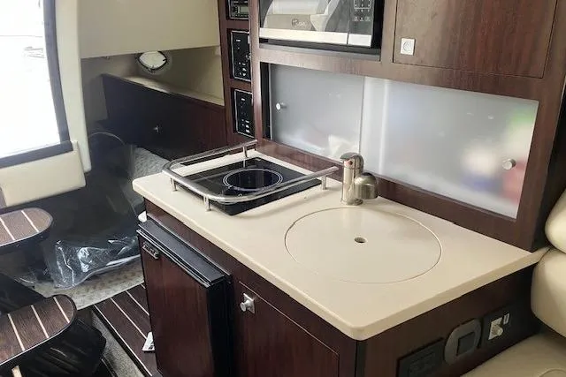 Slide: The Image of Interior of 2016 Monterey 275 Sport Yacht featuring a compact kitchen with stove and sink. - 7