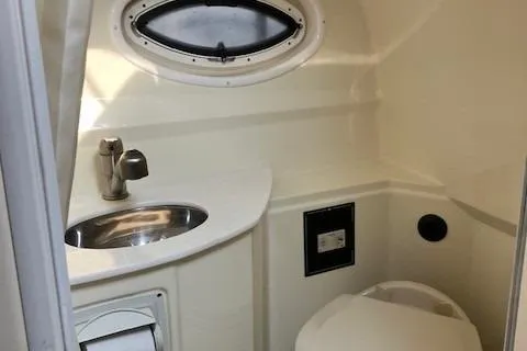 Slide: The Image of 2016 Monterey 275 Sport Yacht bathroom with sink, toilet, and porthole window. - 8
