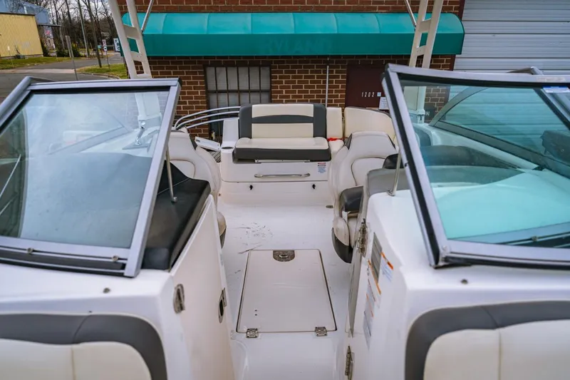 Slide: The Image of 2018 Chaparral 224 Sunesta boat interior with seating and windshield, docked near a brick building. - 4