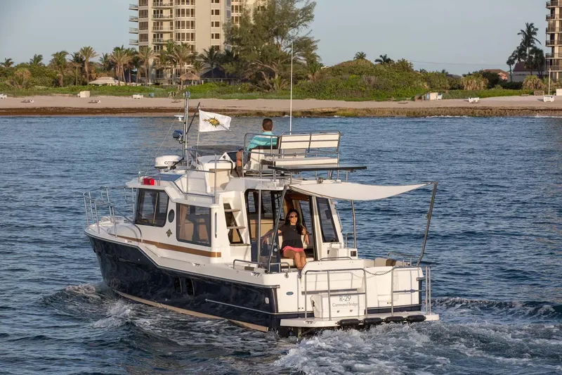 Slide: The Image of 2026 Ranger Tugs R-29 CB cruising near a sandy beach with palm trees. - 3
