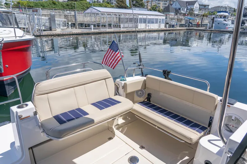 Slide: The Image of 2026 Ranger Tugs R-29 CB boat with seating area and American flag at marina. - 8