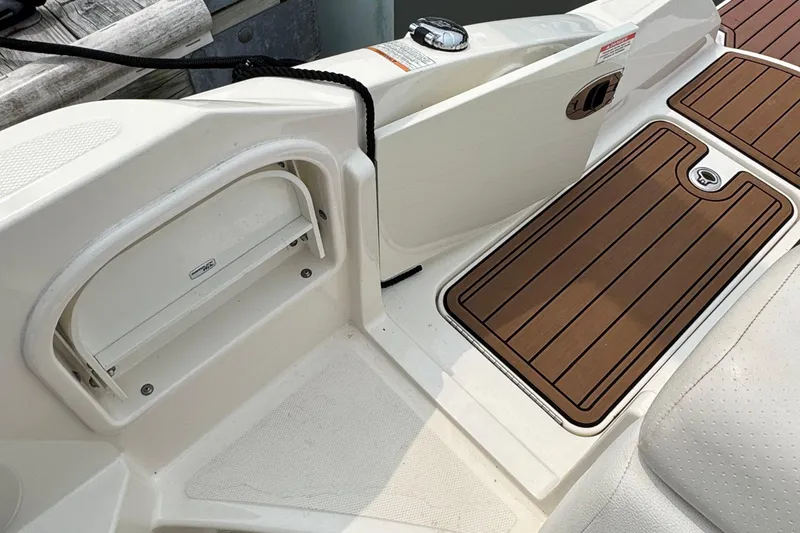 Slide: The Image of 2018 Sea Ray SDX 270 Outboard boat deck with storage compartment and wood-style flooring. - 16