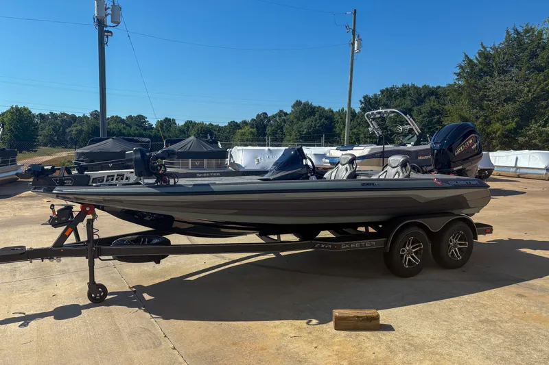 The Image of 2026 Skeeter ZXR 19 boat on trailer, parked outdoors under clear blue sky. - 0