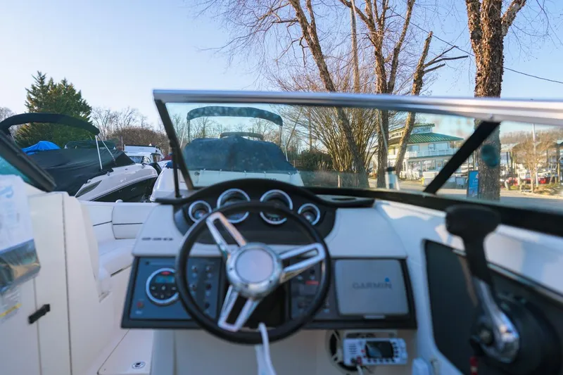 Slide: The Image of 2015 Sea Ray 220 Sundeck boat dashboard with steering wheel and controls, parked outdoors. - 4