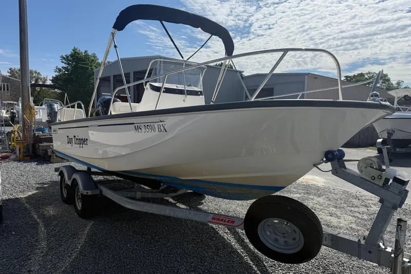 Slide: The Image of 2024 Boston Whaler 190 Montauk boat on trailer, named "Day Tripper," in a marina setting. - 1