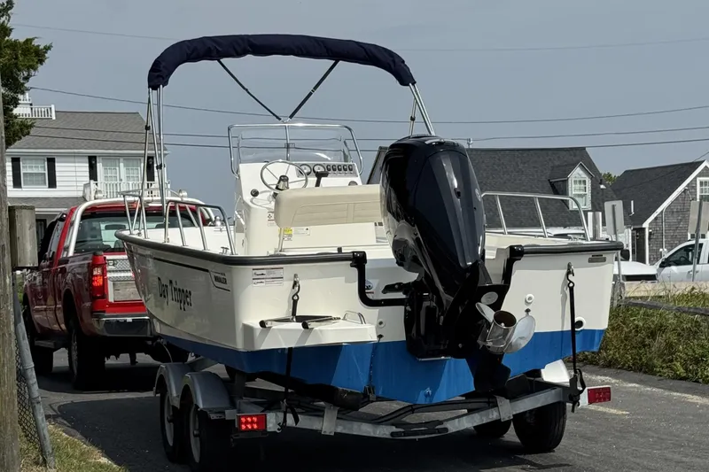 Slide: The Image of 2024 Boston Whaler 190 Montauk boat on trailer, parked near houses. - 7